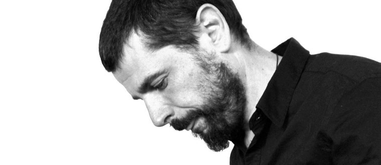 **Alternative Text** Imagen de hombre con el rostro inclinado hacia la derecha, mirando hacia abajo. Lleva un traje de col...